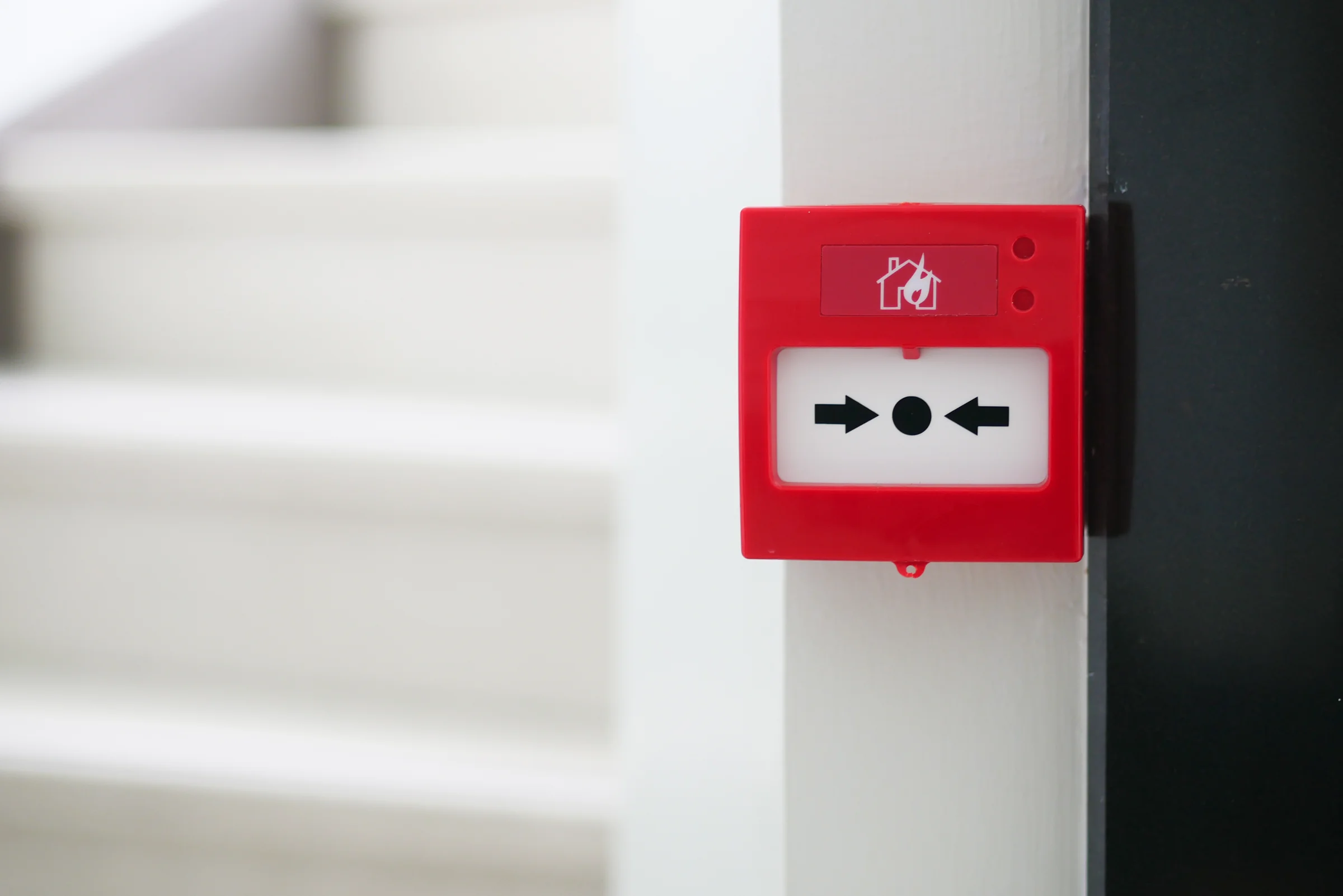 Déclencheur manuel d’alarme incendie rouge fixé au mur, près d’un escalier