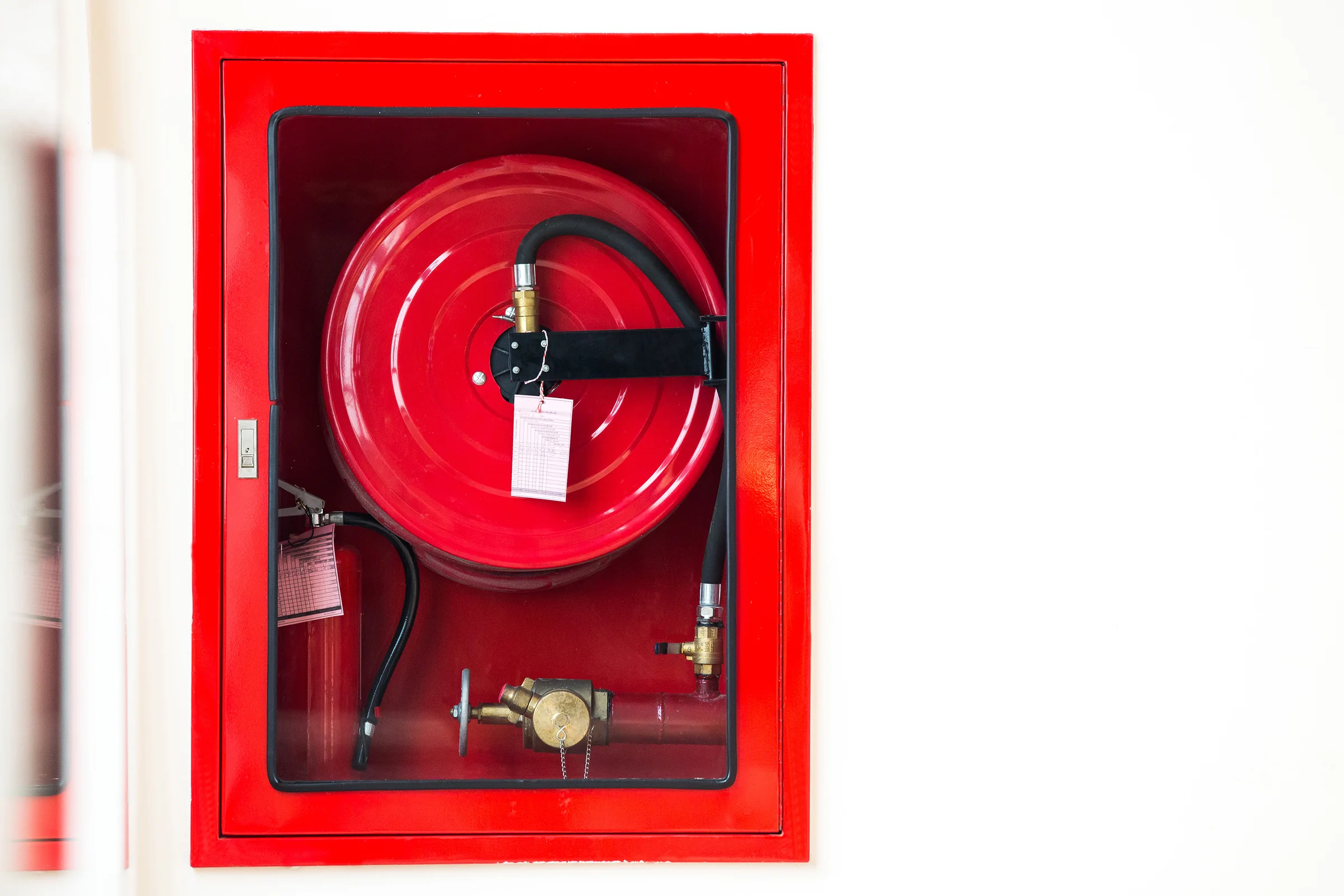 Robinet d’incendie armé (RIA) enroulé dans son armoire rouge vitrée